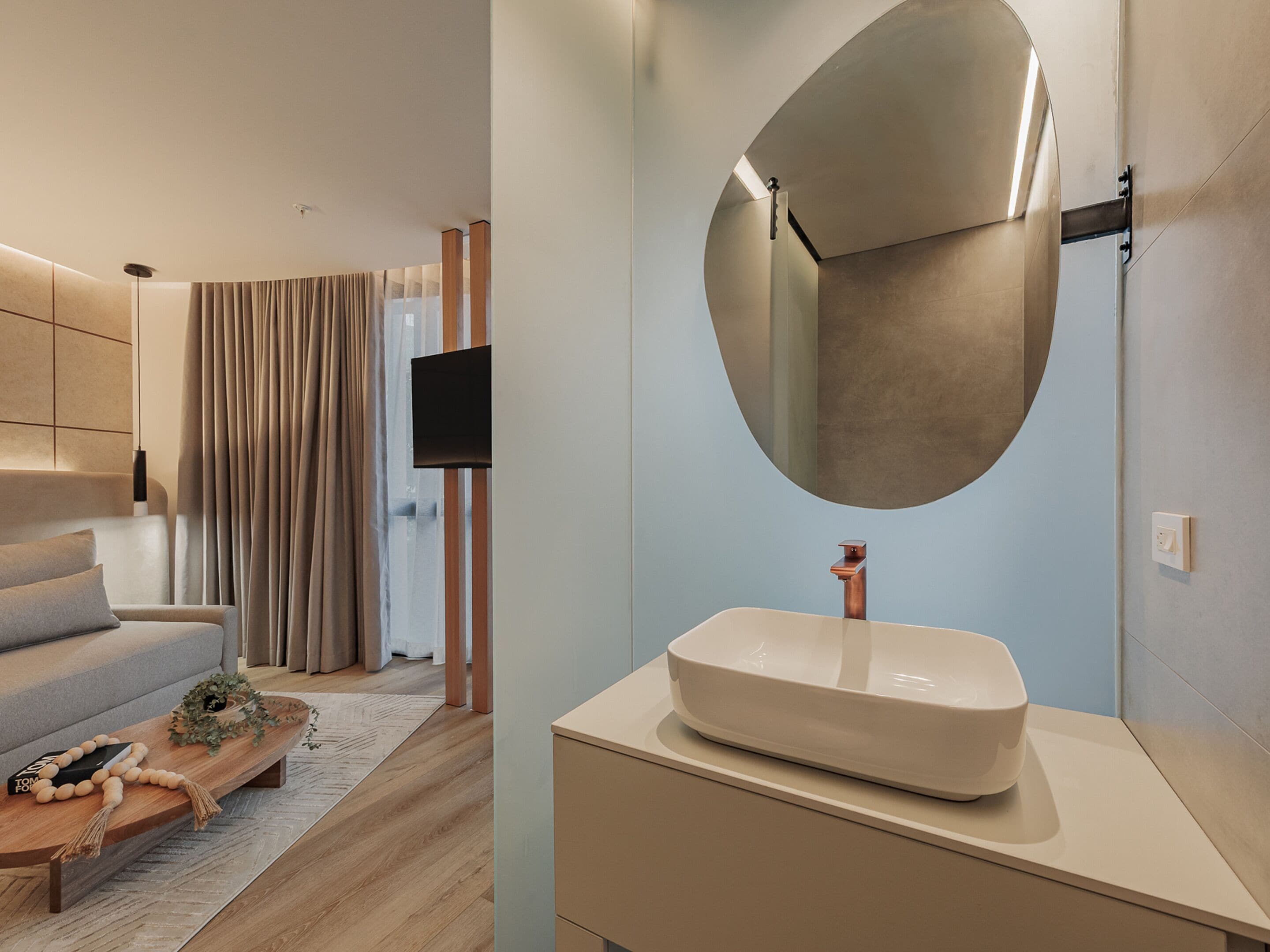 Une salle de bain moderne avec un grand miroir, un lavabo blanc et un design minimaliste.