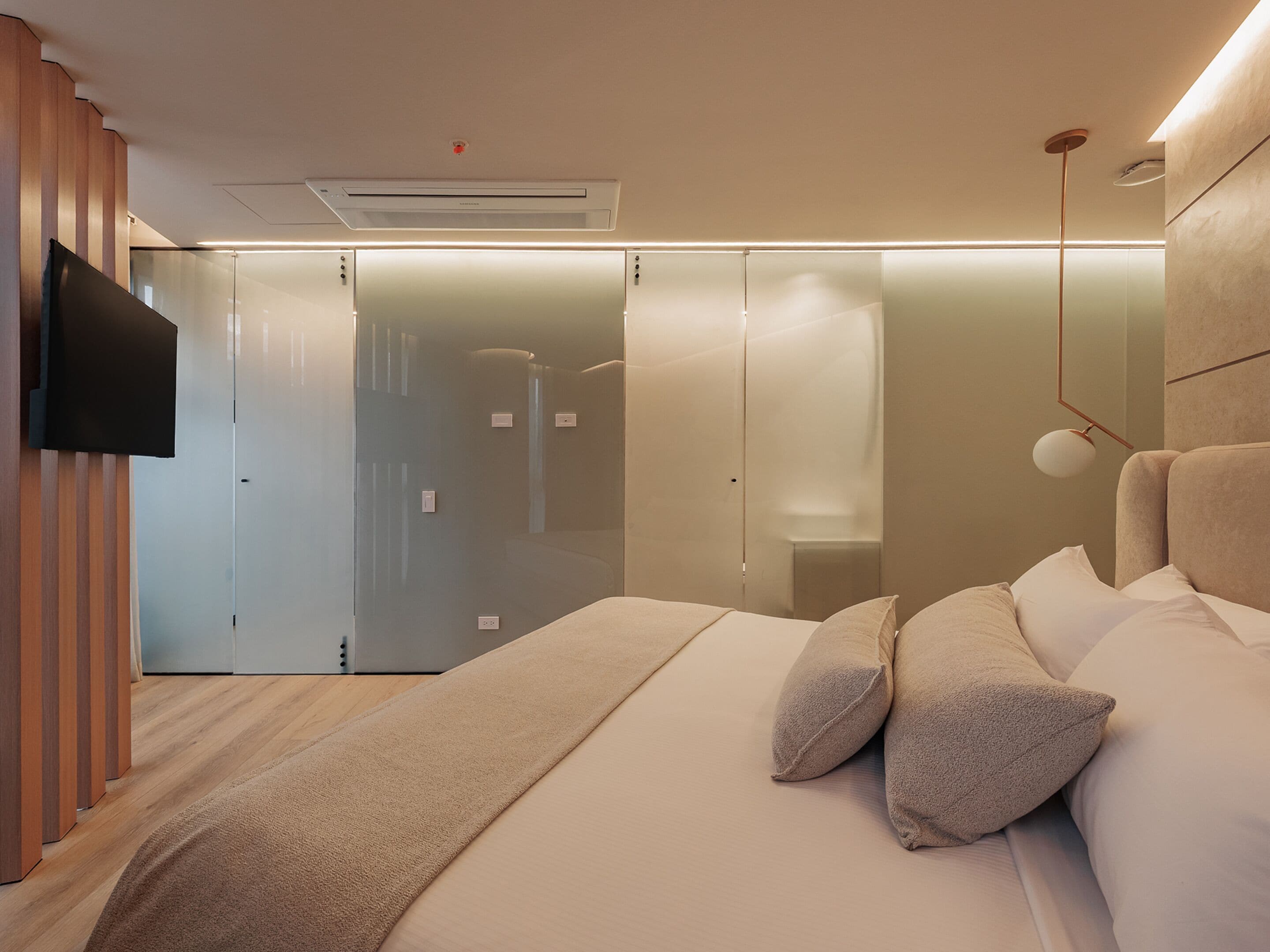 A modern bedroom with a bed, a TV mounted on the wall, and a sliding door closet.