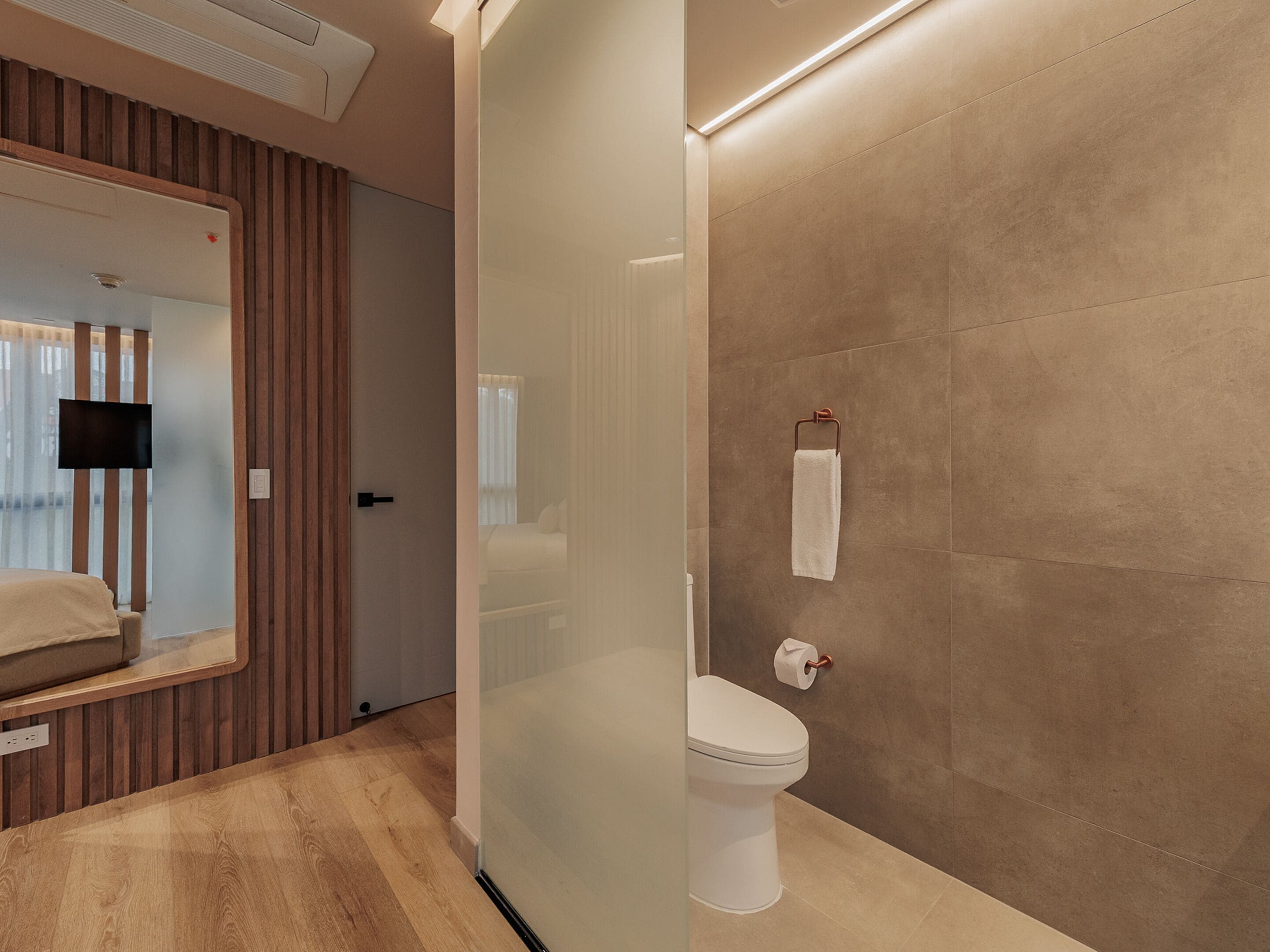 A modern bathroom with a glass partition, a toilet, and a towel rack.