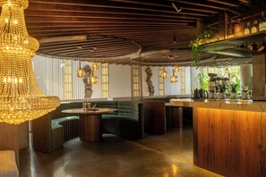 Un interior moderno con techo de madera, una zona de estar verde y una barra.
