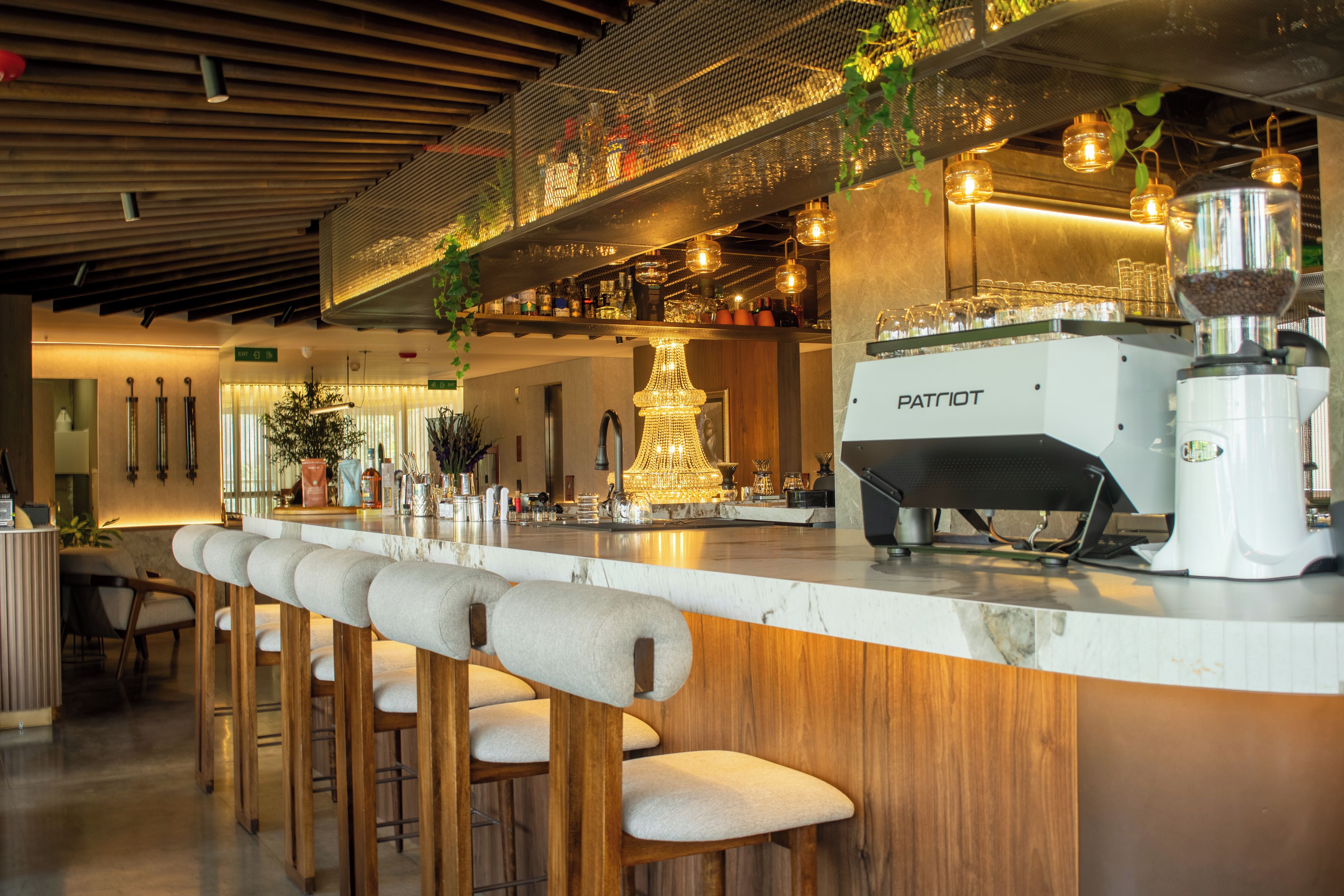 A bar area with a countertop, stools, and a coffee machine.