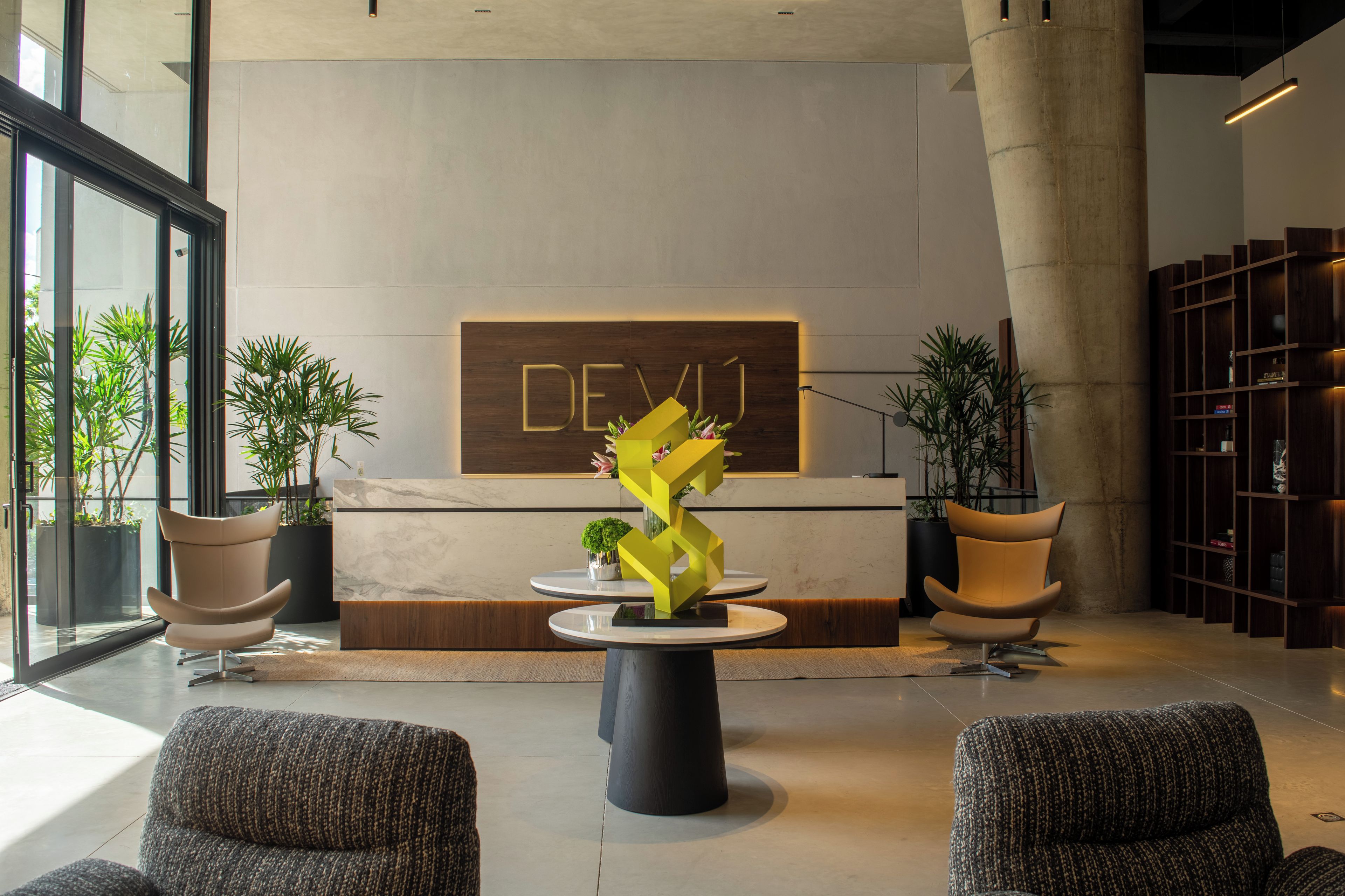 A modern lobby with a reception desk, seating area, and a large wooden sign with the word 'DEVIL' on it.