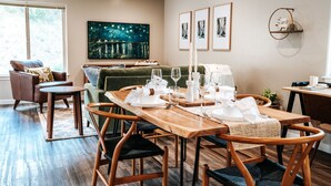 Un comedor con una mesa de madera dispuesta para cuatro personas, rodeado de sillas de mimbre.