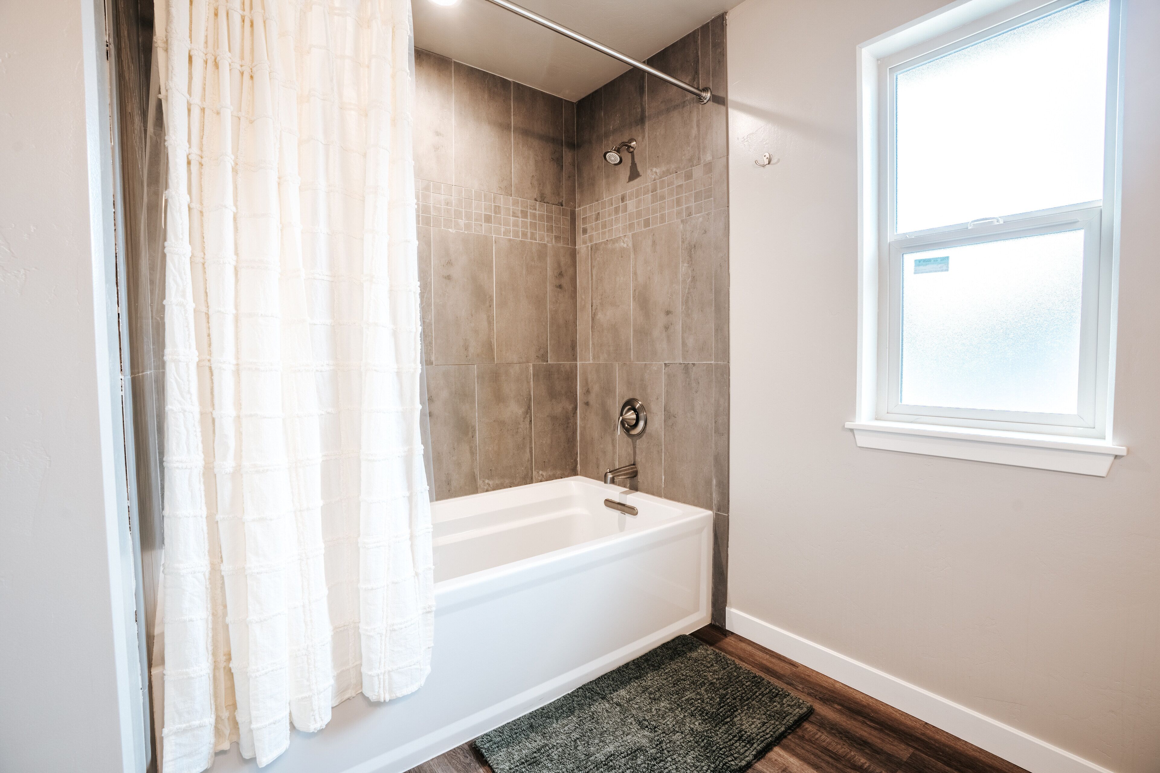 Een badkamer met een bad, een douche en een raam.