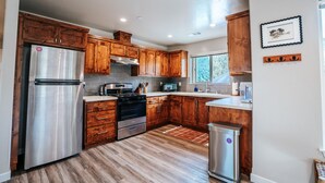 Una cocina moderna con armarios de madera, electrodomésticos de acero inoxidable y un ventanal que proporciona luz natural.