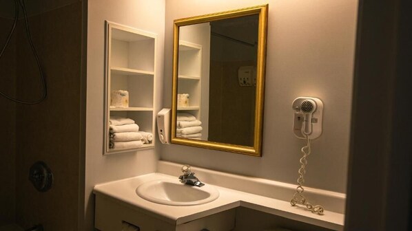 Une salle de bain équipée d’un lavabo, d’un miroir, d’un porte-serviettes et d’un sèche-cheveux.