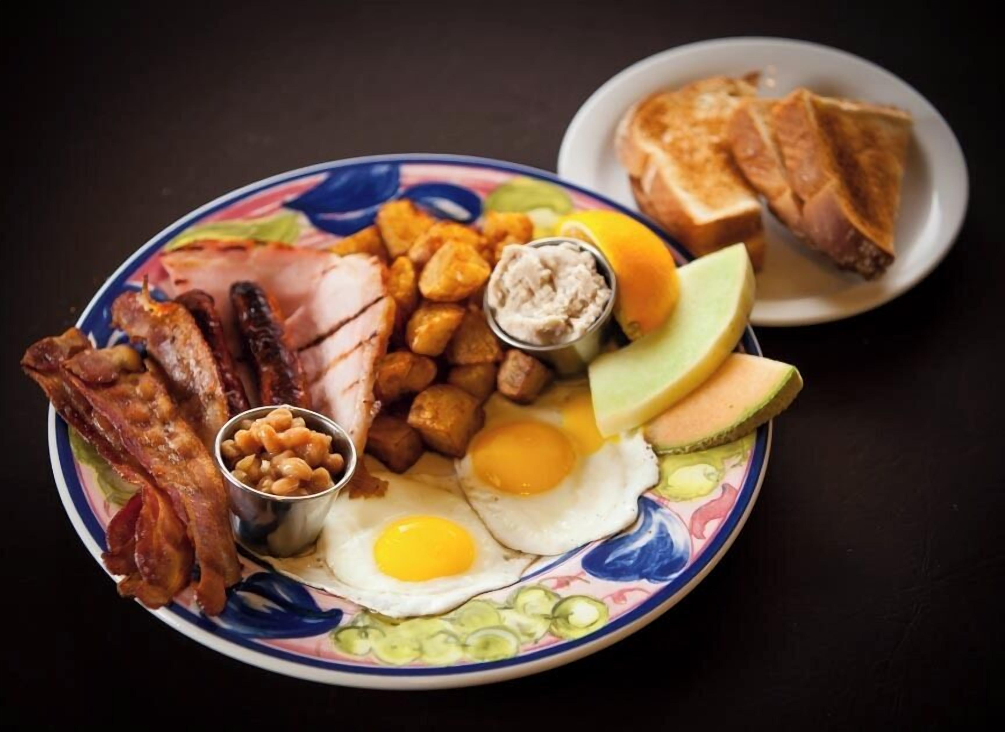 A plate with bacon, eggs, ham, beans, and toast.