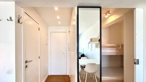 A modern, minimalistic room with a wooden floor, white walls, a white door, and a large mirror. - Zeezicht studio met aparte slaaphoek (Knokke-Heist)