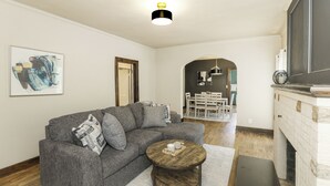 Een woonkamer met een grijze bank, een houten salontafel en een open haard.