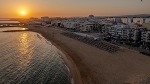 Paesaggio costiero con spiaggia, edifici e un tramonto.