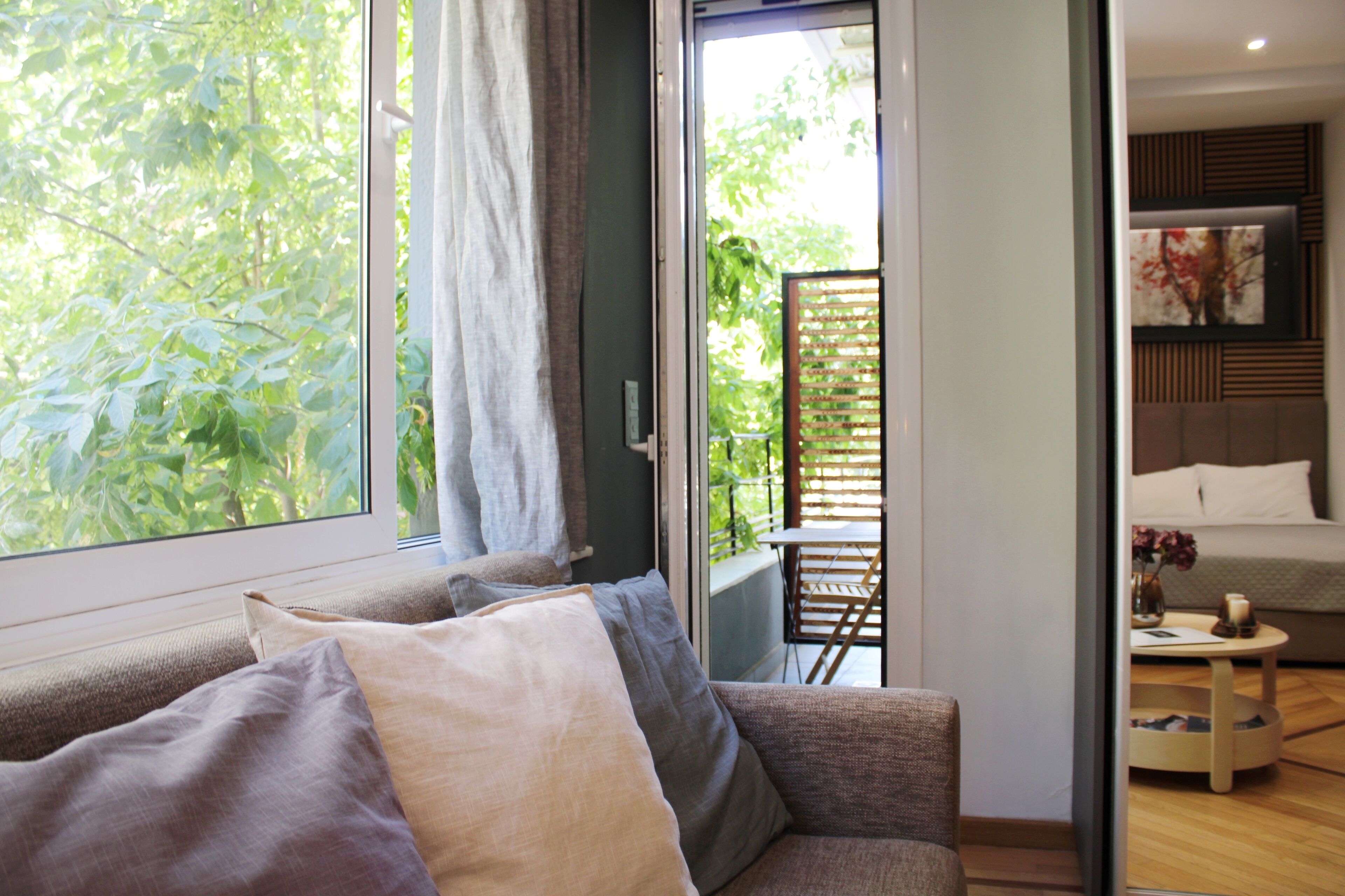 A modern living room with a sofa, a small table, and a view of a balcony with a wooden fence.