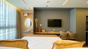 A modern hotel room with a large bed, a TV mounted on the wall, a bedside table with a lamp, and a window with sheer curtains. - Acqua Tambaú Prime - By Almare (João Pessoa)