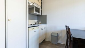 Une cuisine de taille réduite avec des meubles blancs, un four à micro-ondes et une petite poubelle.