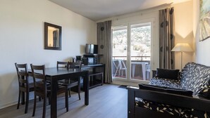 Un espace de vie compact comprenant un coin repas, un canapé, un téléviseur et un balcon avec vue.