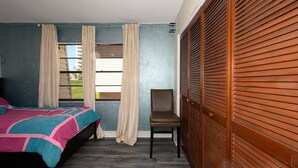 A bedroom with a bed, a chair, a window with curtains, and a wooden closet. - Spacious, privet entry retreat 2 min walk to Worlds Famous Beach! (Daytona Beach Shores)