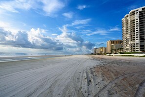 A beach with a sandy shore and a row of multi-story buildings in the background. - Spacious, privet entry retreat 2 min walk to Worlds Famous Beach! (Daytona Beach Shores)