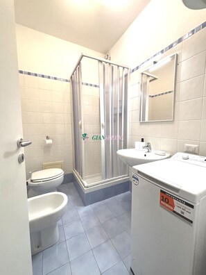 Une salle de bain équipée de toilettes, d’un bidet et d’une douche.