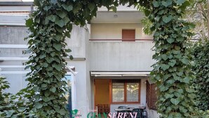 Um caminho leva a um edifício com entrada coberta, emoldurada por hera.