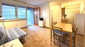 Um espaço compacto com cozinha americana, área de refeições e quarto com cama e mesa de cabeceira.