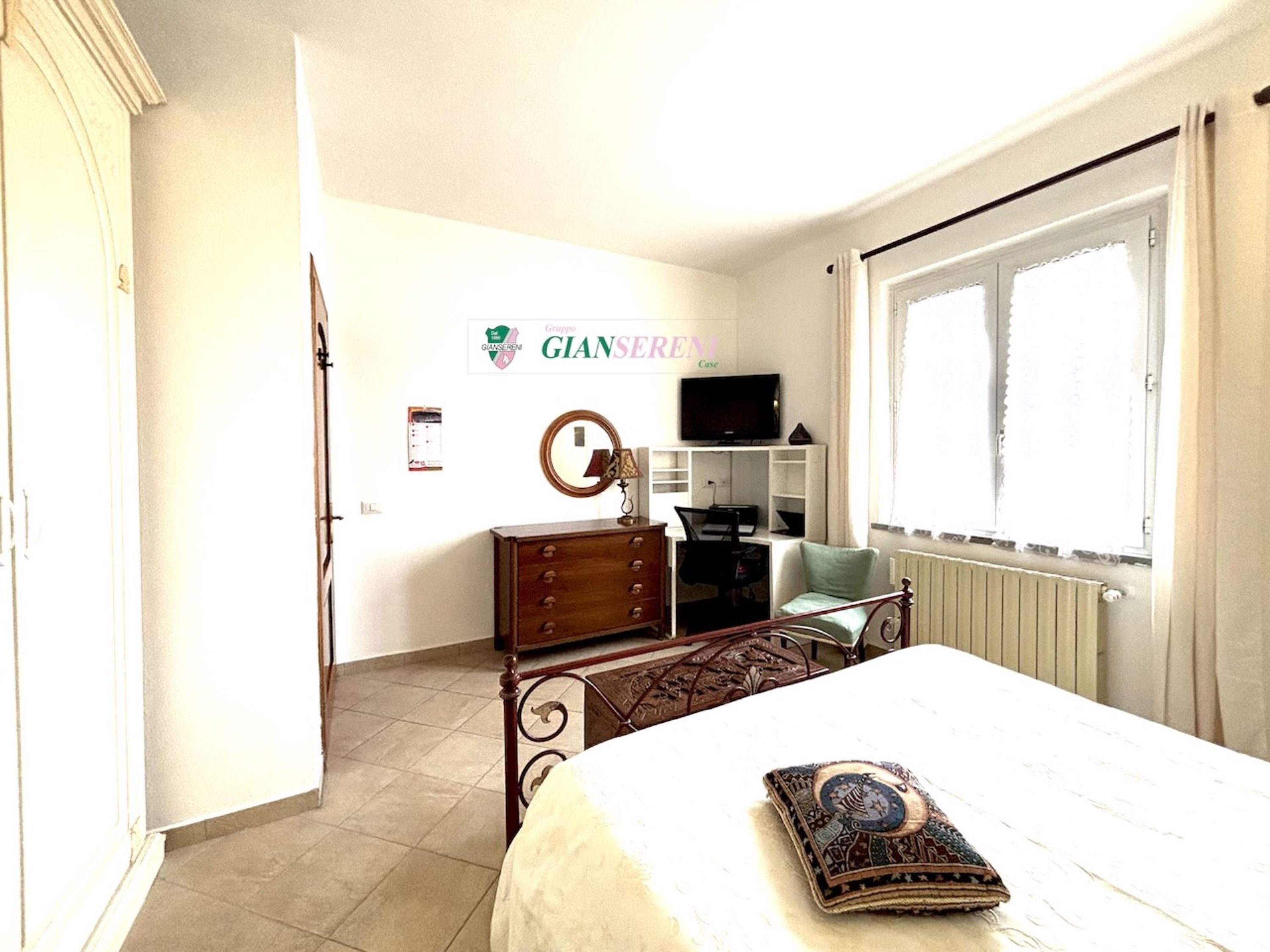 Une chambre à coucher comprenant un lit, une commode, un bureau, une chaise et un téléviseur.
