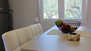 Ett modernt kök med ett vitt bord, en vit soffa och ett fönster med utsikt över träd.