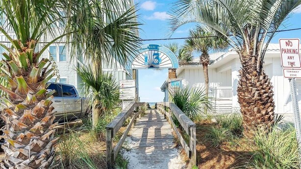 A wooden boardwalk leading to a beach entrance, surrounded by palm trees and a sign indicating no parking at any time. - Sand Castle Serenity Studio - Sleeps 4 - Steps to the Beach - No Extra Fees (Panama City)