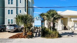 A beachfront property with a wooden deck, a sign reading "Private Property," and a building with a white facade. - Sand Castle Serenity Studio - Sleeps 4 - Steps to the Beach - No Extra Fees (Panama City)