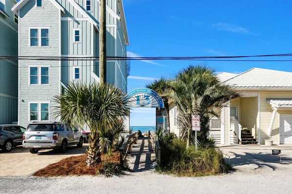 A beachfront property with a wooden deck, a sign reading "Private Property," and a building with a white facade. - Sand Castle Serenity Studio - Sleeps 4 - Steps to the Beach - No Extra Fees (Panama City)