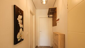 Un corridoio con un mobile in legno, una porta bianca e una mensola a muro.