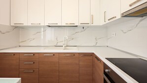 Una cocina moderna con gabinetes blancos, salpicadero de mármol y encimera negra.