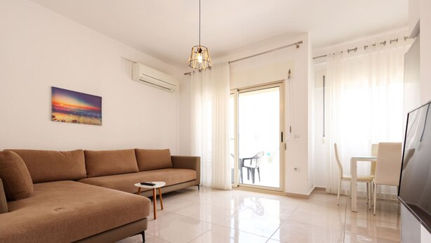 Una sala de estar moderna con un sofá marrón, una mesita redonda pequeña, un televisor y un cuadro en la pared.