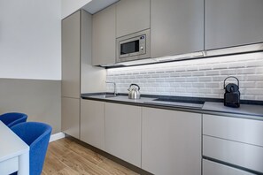 Eine moderne Küche mit Mikrowelle, Wasserkocher und Kaffeemaschine auf der Arbeitsfläche.