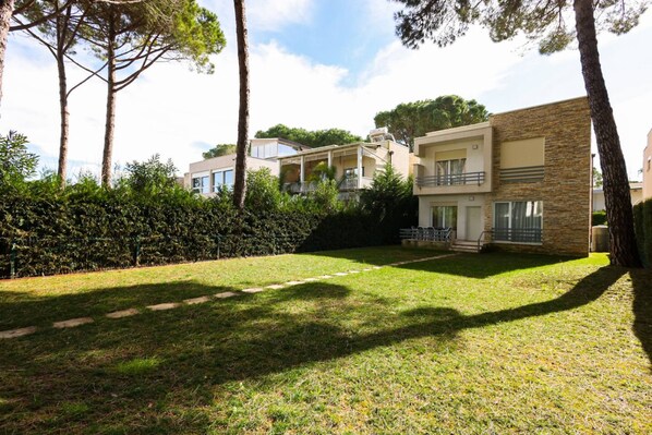 A residential area with modern houses, a well-maintained lawn, and tall trees.