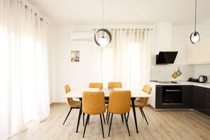 A modern kitchen with a dining area, featuring a white table, four chairs, and a TV mounted above the counter.