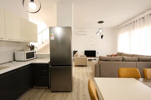 A modern kitchen with a built-in refrigerator, a microwave, and a dining area with a table and chairs.