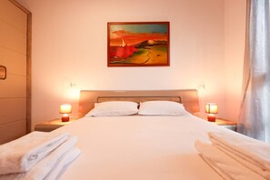 Une chambre d’hôtel avec un lit, deux lampes de chevet, un tableau au mur et une fenêtre avec des rideaux.