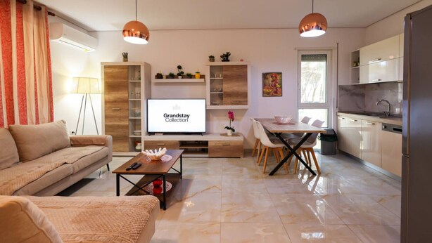 Una sala de estar moderna con sofá, mesa de centro, televisor y comedor.