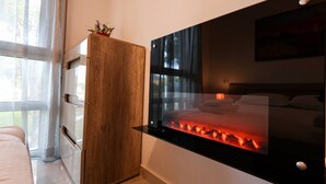 Un dormitorio moderno con una plataforma de cama de vidrio, un armario de madera y un ventanal grande.