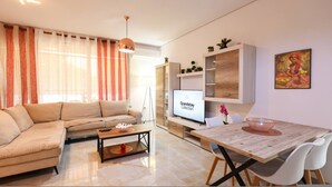 Una sala de estar moderna con un sofá, una mesa de centro, un televisor y un comedor con sillas y una mesa.