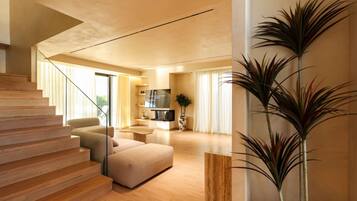 A modern living room with a staircase, a flat-screen TV, and a large plant.