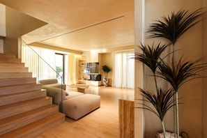 A modern living room with a staircase, a flat-screen TV, and a large plant. - Private Pool Oasis | Beach Resort (Plazhi San Pietro)