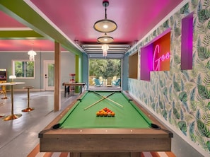A pool table with a neon sign, a pool table in a room with a green pool table, and a pool table in a room with a green pool table.