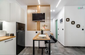 Une cuisine moderne dotée d’un téléviseur encastré, d’un mur recouvert de panneaux en bois et d’un coin repas avec une table dressée pour deux personnes.