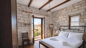 Ein Schlafzimmer mit Steinsturz, einem hölzernen Bett, einem Sessel und einem Fenster mit Blick auf ein Gebäude.