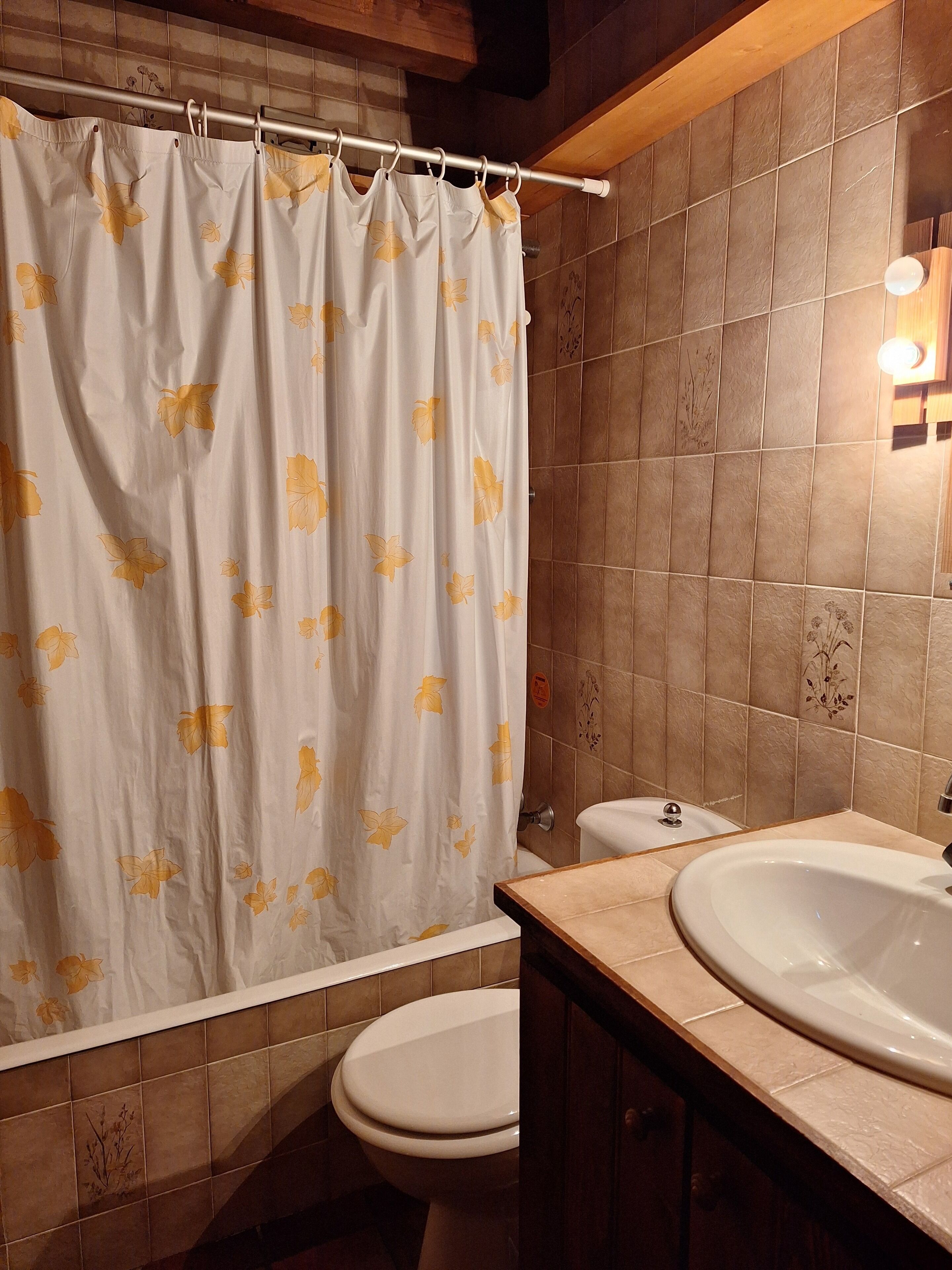 A bathroom with a shower curtain, a toilet, and a sink.