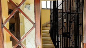 Eine Holztür mit einem geometrischen Muster, die zu einer Treppe mit einem schwarzen Metallgeländer führt.