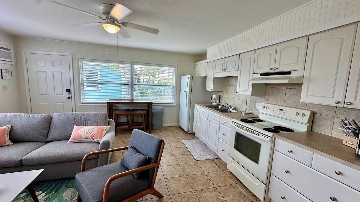 A compact living space with a kitchenette, a sofa, a dining table, and a ceiling fan.