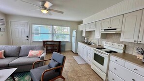 A compact living space with a kitchenette, a sofa, a dining table, and a ceiling fan. - SunShell 3 - Steps from Sand (Fort Myers)