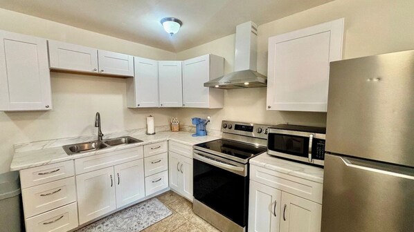 A modern kitchen with white cabinetry, stainless steel appliances, and a built-in microwave. - SunShell 1 - 4 min walk to Beach (Fort Myers)
