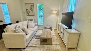 Ein Wohnzimmer mit einer Couch, einem Couchtisch, einem Fernseher auf einem Schrank und einer Lampe.